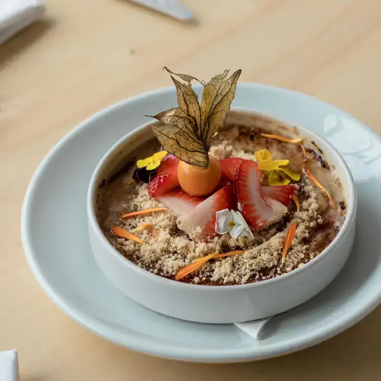 A dessert decorated with strawberries and flowers with a physalis on top from Gezellig, one of the best brunch spots in Ottawa.