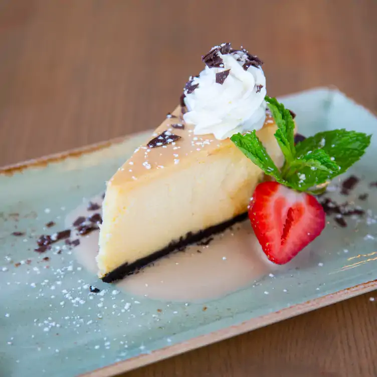 A slice of cheesecake decorated with chocolate chunks, strawberries, and whipped cream from Milestones Grill + Bar, one of the best brunches in Ottawa.