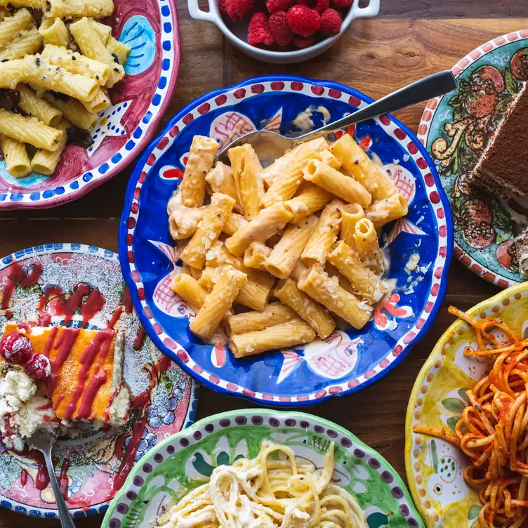 Une table avec de nombreuses assiettes de pâtes différentes et deux desserts chez La Casina, l’un des meilleurs restaurants familiaux de Montréal.