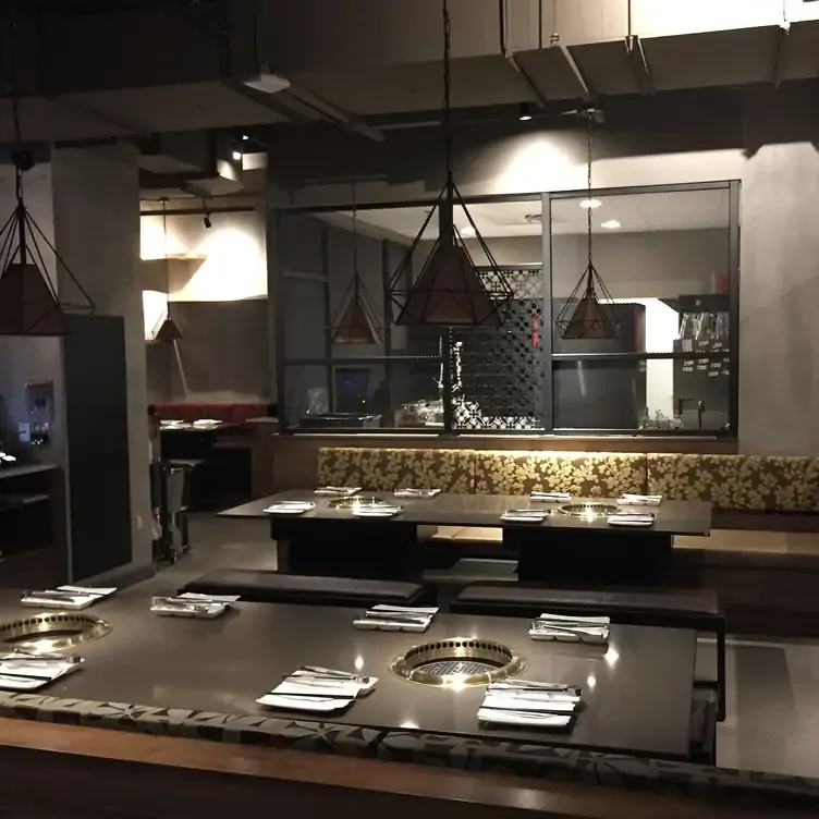 Une salle de restaurant avec des décorations asiatiques et plusieurs tables avec au centre un grill personnel chez Gyu-Kaku, l’un des meilleurs restaurants familiaux de Montréal.