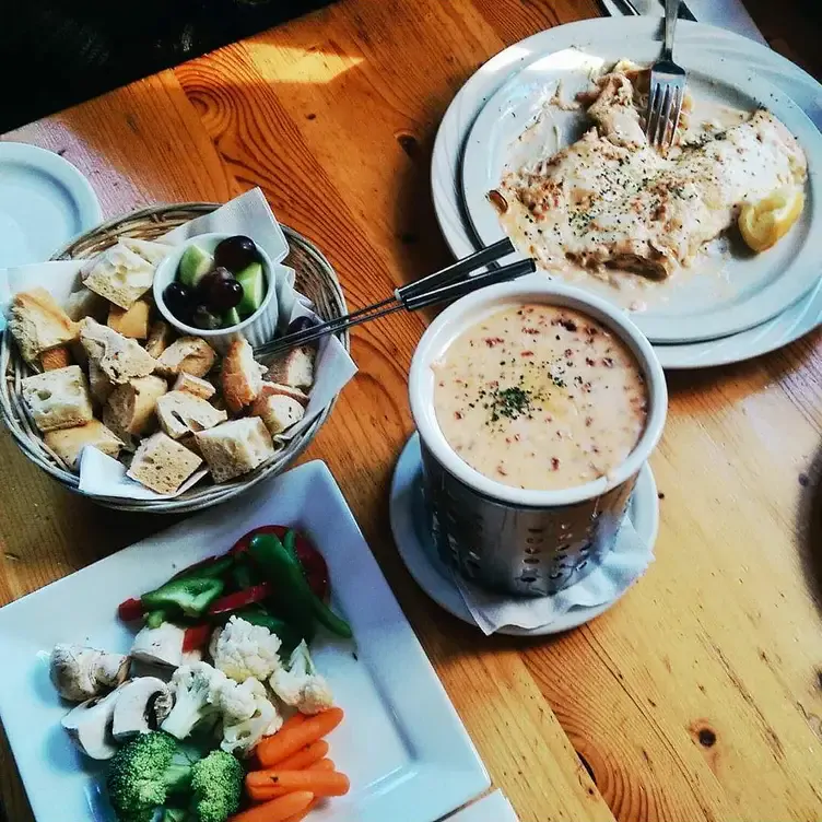 Une corbeille de pain accompagnant une fondue, une assiette de légumes et une crêpe salée chez Crêperie Chez Suzette Inc, l’un des meilleurs restaurants familiaux de Montréal.