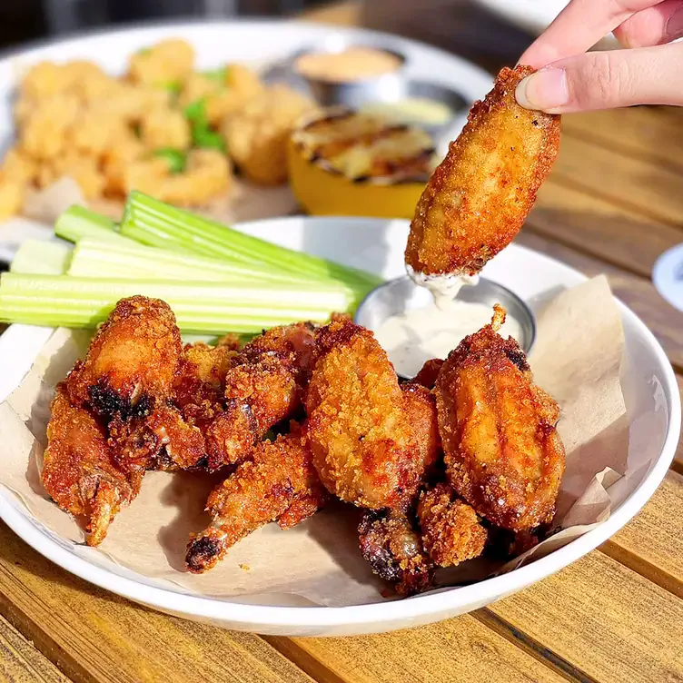 A plate filled with crispy chicken wings, celery, and a dip from Moxies, one of the best family restaurants in Edmonton.