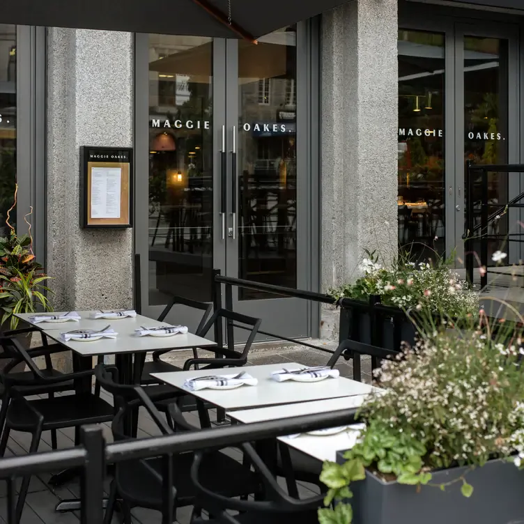 Une terrasse avec plusieurs tables à côté de la porte d’entrée de chez Maggie Oakes, l’un des meilleurs restaurants familiaux de Montréal.