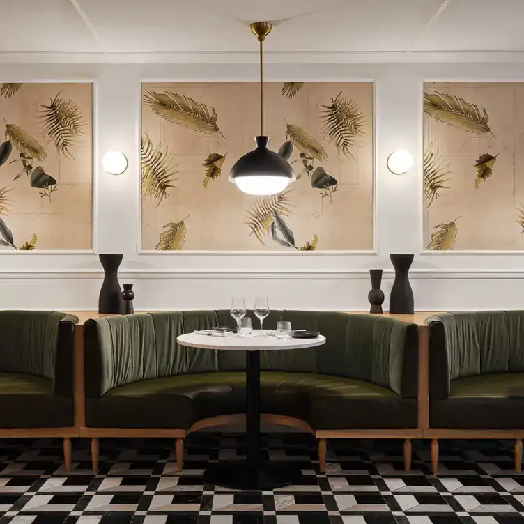 A table surrounded by dark green banquettes in a bright room with black and white tiled flooring from Cocotte Bistro, one of the best brunches in Ottawa.