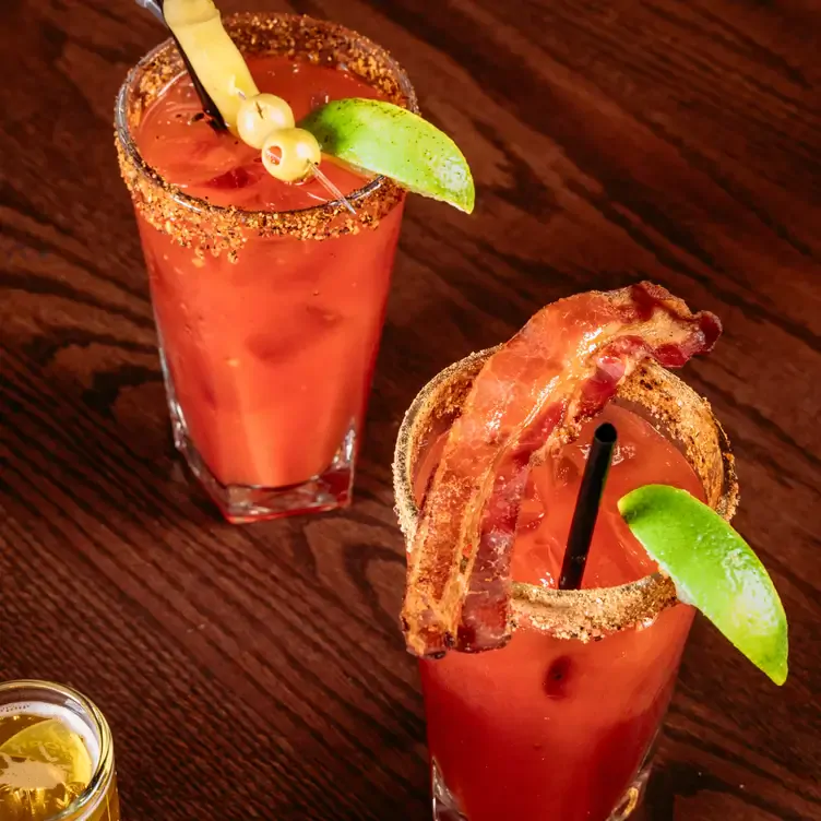 Two glasses of Bloody Mary one with lime and bacon, and the other with lime and olives from Mr Mikes SteakhouseCasual, one of the best family restaurants in Edmonton.