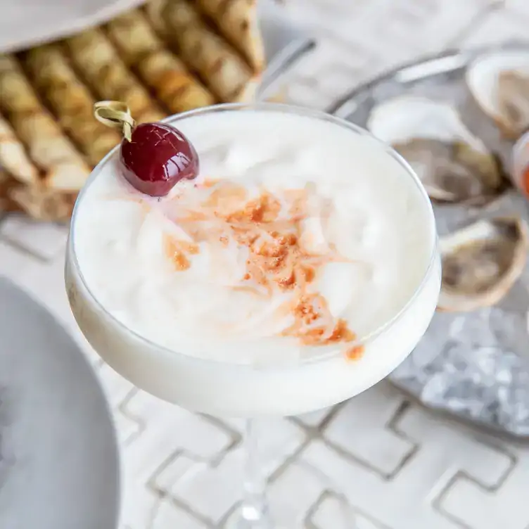 A white cocktail with oysters at KŌST, one of the best rooftop restaurants Toronto offers.