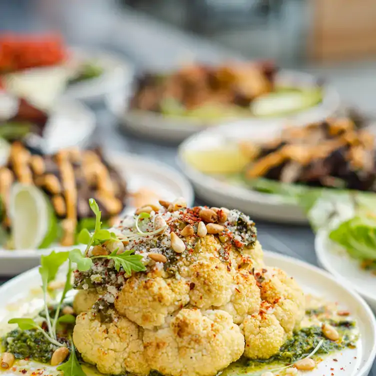 Une assiette avec un morceau de chou-fleur assaisonné reposant sur une sauce verte chez Nacarat, l’un des meilleurs restaurants sur le toit à Montréal.