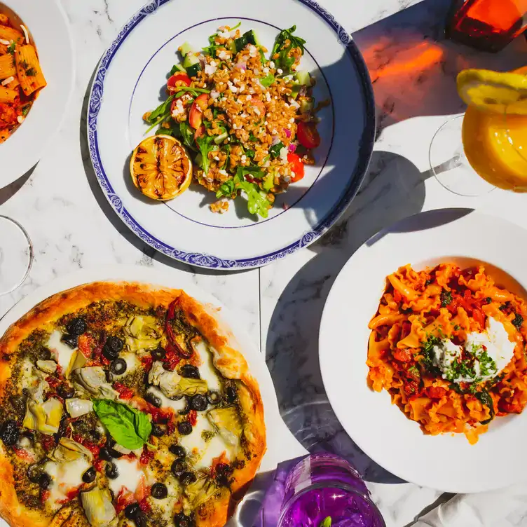 Pizza, pasta, and salad on a sun-drenched patio at Pie Bar Pizzeria, one of the best waterfront restaurants in Toronto.