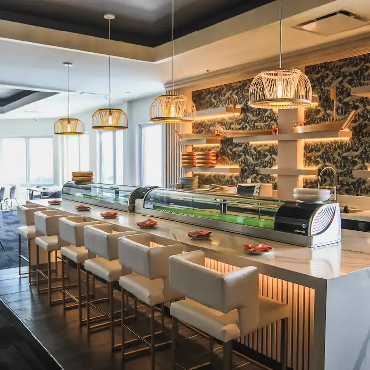 A bright bar under suspended lamps, in front of a wall adorned with golden carp wallpaper at Restaurant Kato, one of the best restaurants with a view in Ottawa.