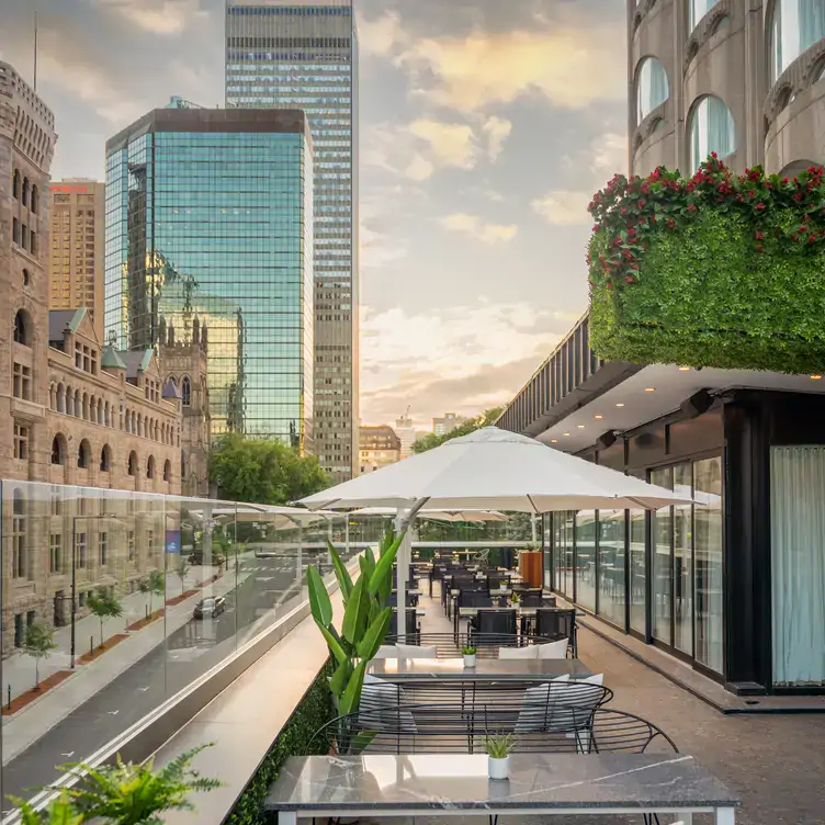 Une terrasse avec des parasols donnant sur la ville en fin d’après-midi chez Belvu, l’un des meilleurs restaurants sur le toit à Montréal.