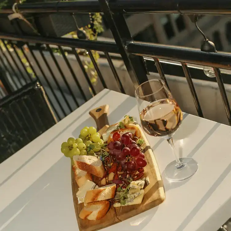 Un plateau de fromages et de fruits accompagné d’un verre de vin à la Terrasse Place d’Armes, l’un des meilleurs restaurants sur le toit à Montréal.