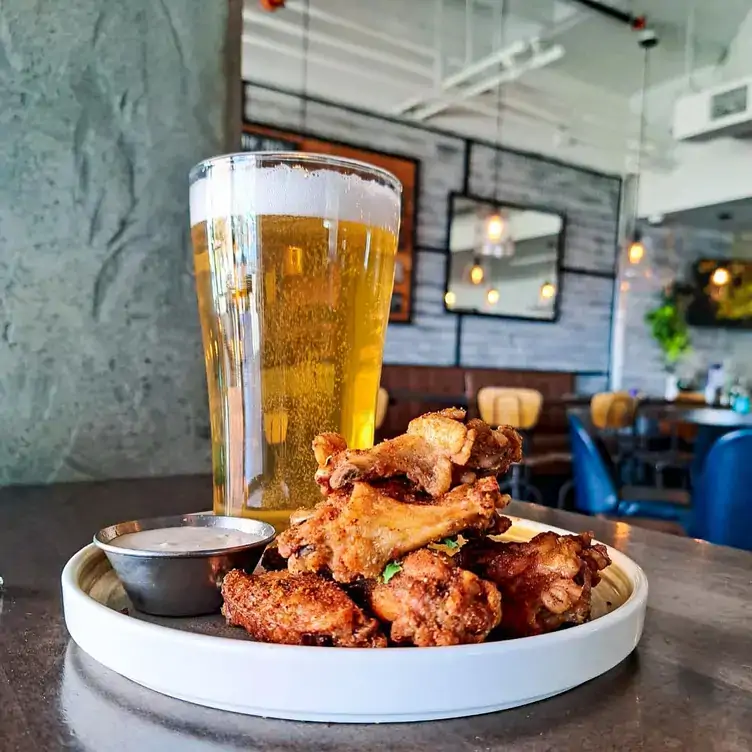 A cold glass of beer with chicken wings at Hook Restaurant, one of the best view restaurants found in Vancouver.