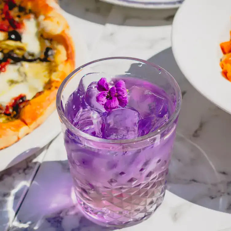 A purple cocktail on a patio at Pie Bar Pizzeria, one of the best Harbourfront restaurants in Toronto.