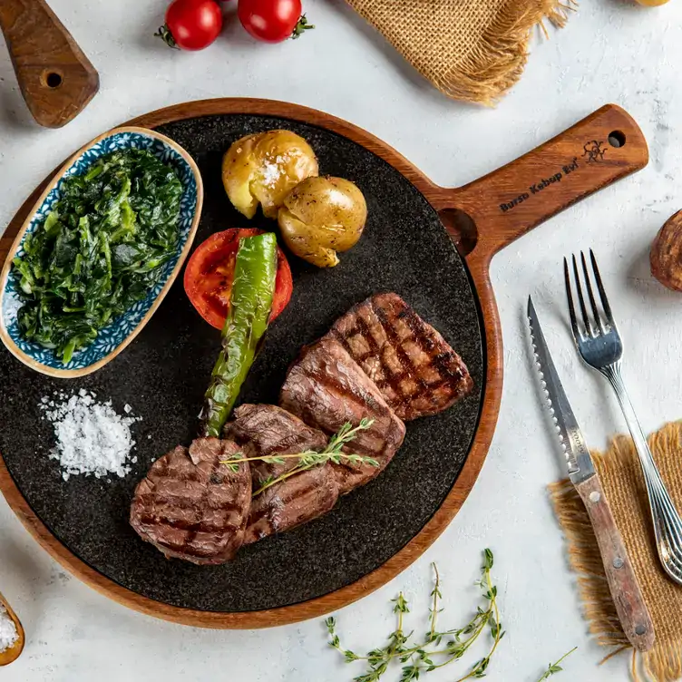 A steak served on a skillet with spinach, tomato and asparagus and crushed potatoes at Bursa Kebap Evi Ltd., one of the best halal restaurants in Toronto.