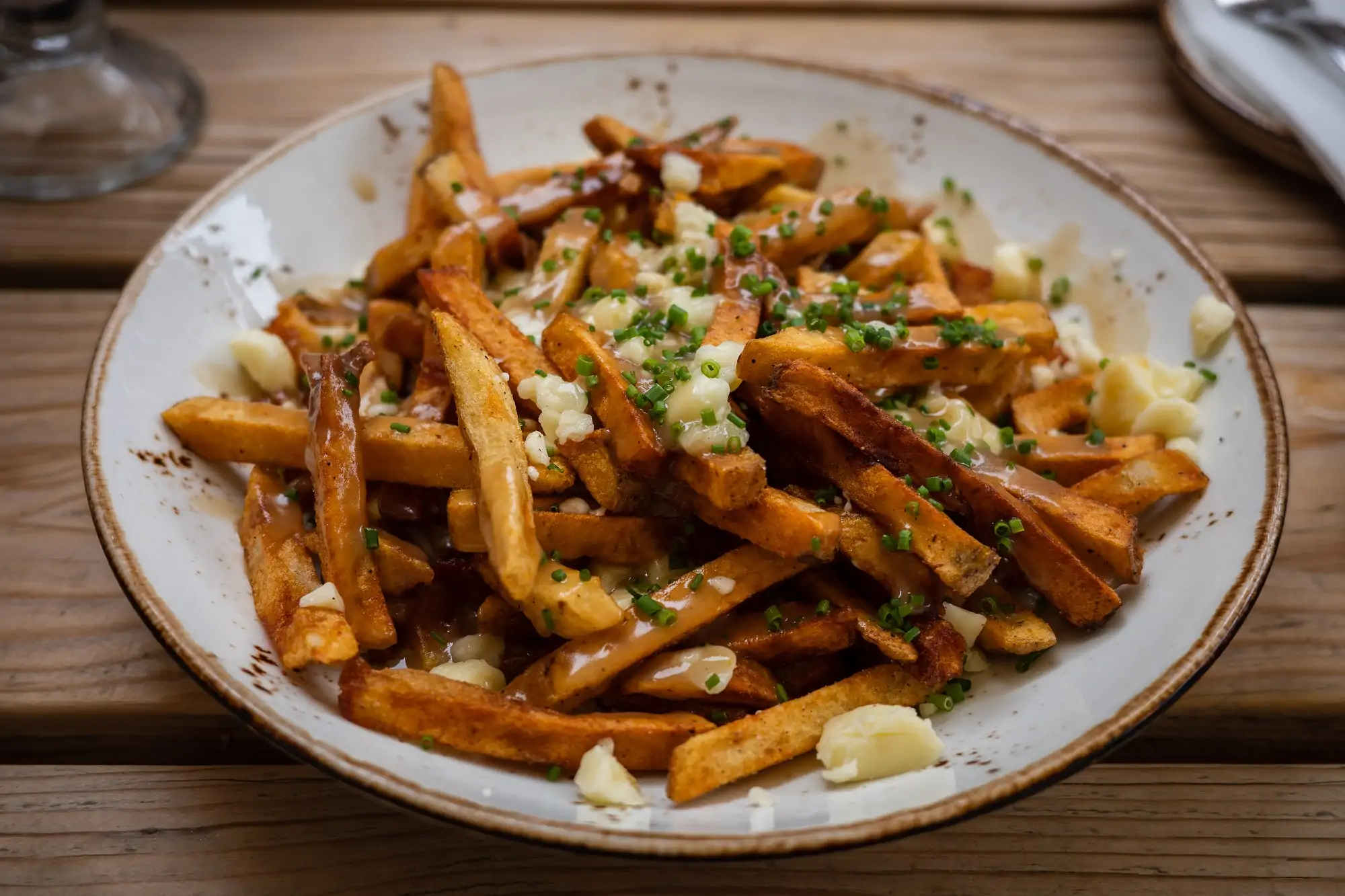 A bowl of some of the best poutine in Montreal, fries covered in cheese curds and gravy.