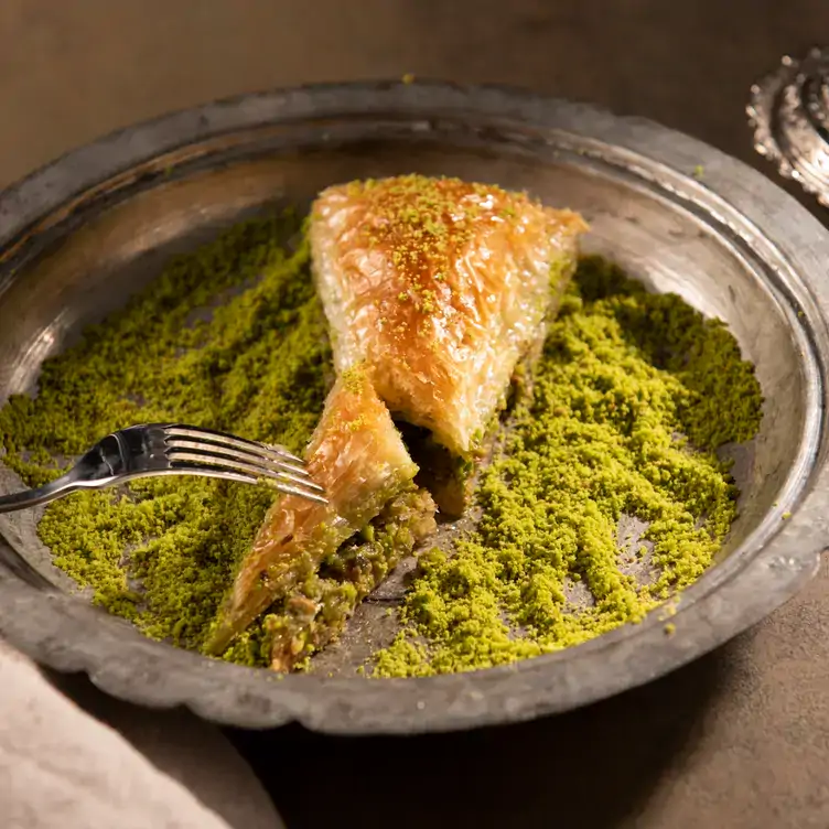 A closeup of baklava served on a silver platter in a bed of finely ground pistachio from Bursa Kebabp Evi Ltd., one of Toronto’s best Turkish restaurants.