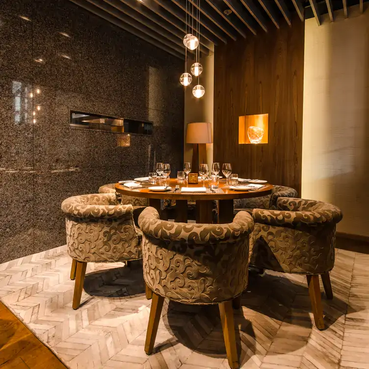 A table in the Montreal private dining room of Maison Boulud, set for six with wine glasses on a round table.