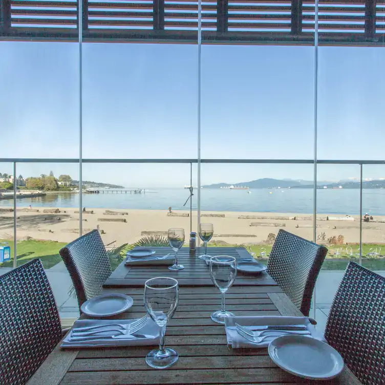 A dining table with views over the beach at The Boathouse at Kits Beach