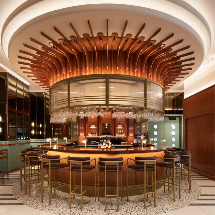 The bar area of Commodore, one of the best restaurants in downtown Montreal, with stools set around a circular bar.