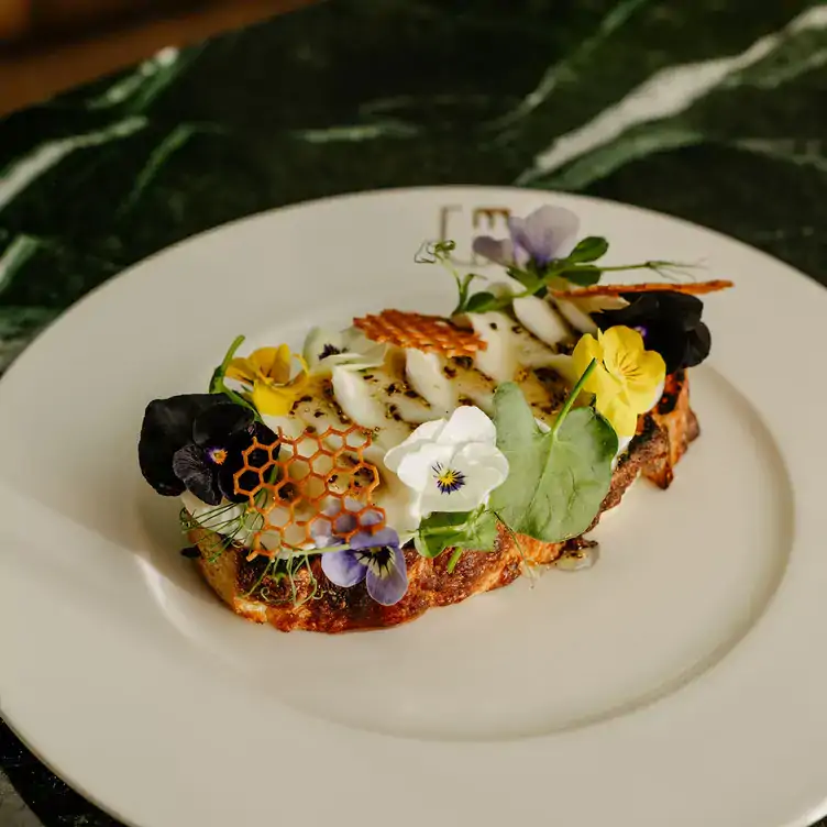 A vegan dish featuring an eggplant topped with flowers at Marcus, one of the best vegan restaurants in Montreal