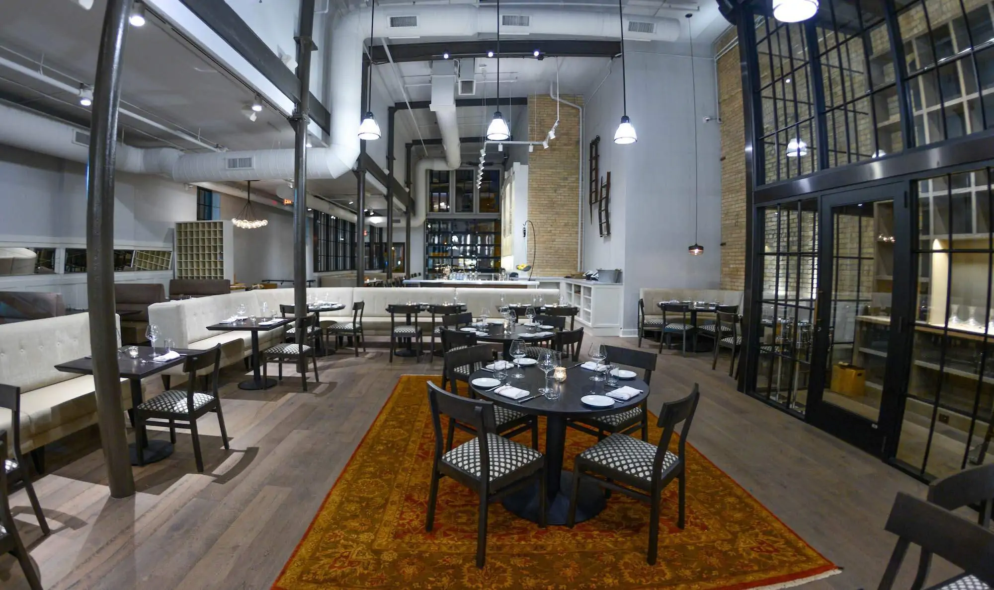 A restaurant dining room with several tables located in different areas of the restaurant. The design is modern and vibrant