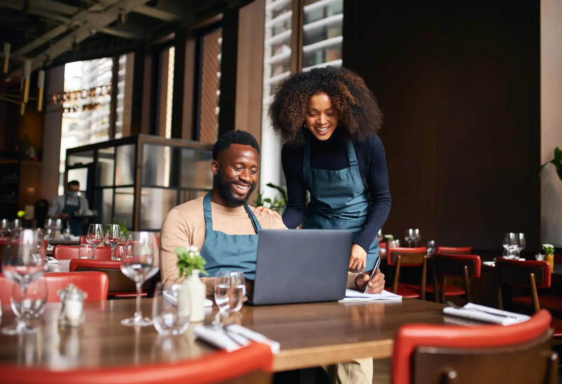 Two restaurant owners are working on a laptop in a restaurant